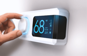 A human hand adjusting the settings of a smart thermostat