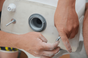 A human hand fixing the problems of a running toilet