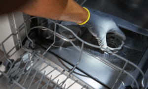 A plumber cleaning the filter basket of a dishwasher 