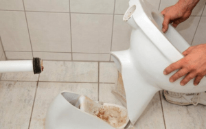 A plumber replacing a broken toilet in the washroom