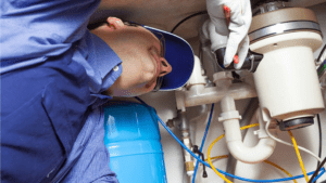 A plumber taking out glass peices from the garbage disposal by using tools