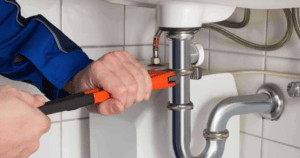 Plumber fixing the pipe with wrench