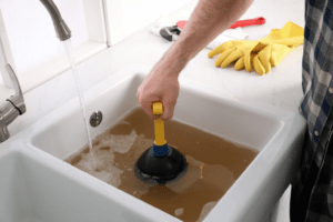 Using a plunger for clearing the drains and unclogging the basin
