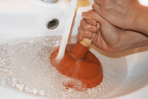 Woman using a plunger to unclog a bathroom sink