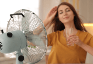 Young women enjoying cold wind from the fan